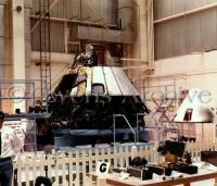 Officer stands guard next to disassembled Apollo 204 command module 