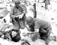 Medics help wounded soldier, Omaha Beach 