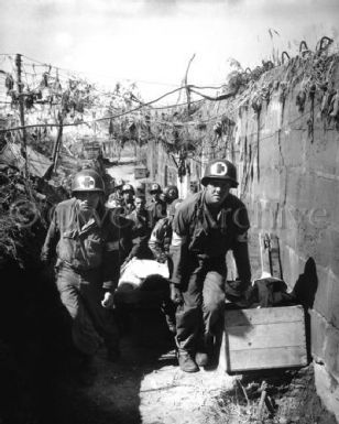 Medics carry wounded soldiers in German trench, Omaha Beach